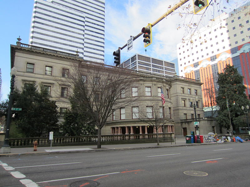 A horizontal building seen from an angle with larger surrounding structures.