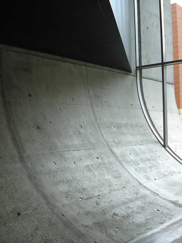 A concrete wave seen from the interior of the Center for Contemporary Art. The wave of concrete visually pushes through the glass windows and can be seen, continuing, to the exterior as well.