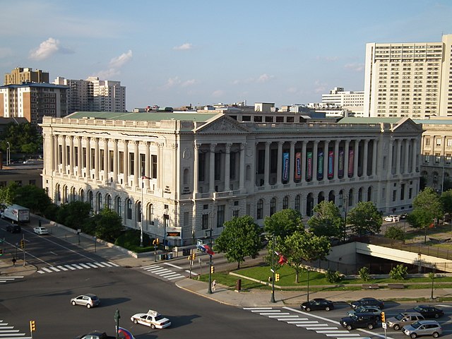 A Beaux-Arts style building on a city block. The building is white marble with ornate designs, such as columns and pediments.