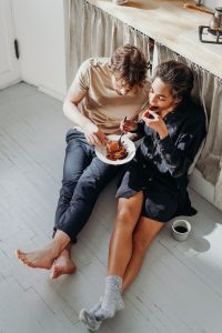 man and woman sharing breakfast while sitting on the floor