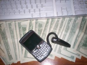 Photo display of a laptop computer on a stack of $100 bills.