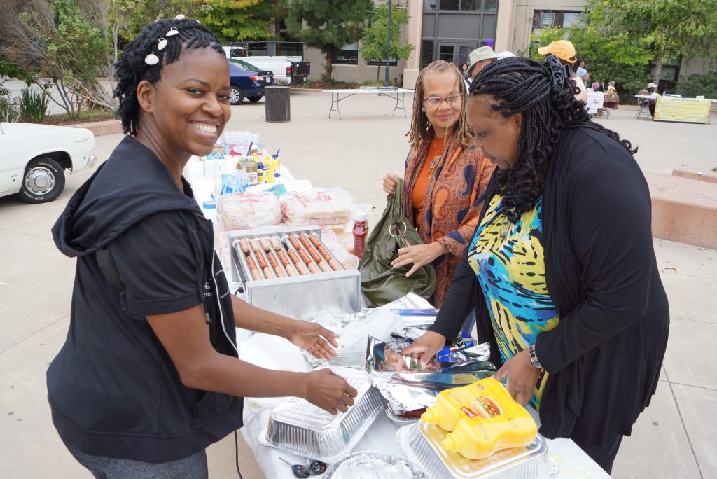 Three Black women setting up food for a picnic.