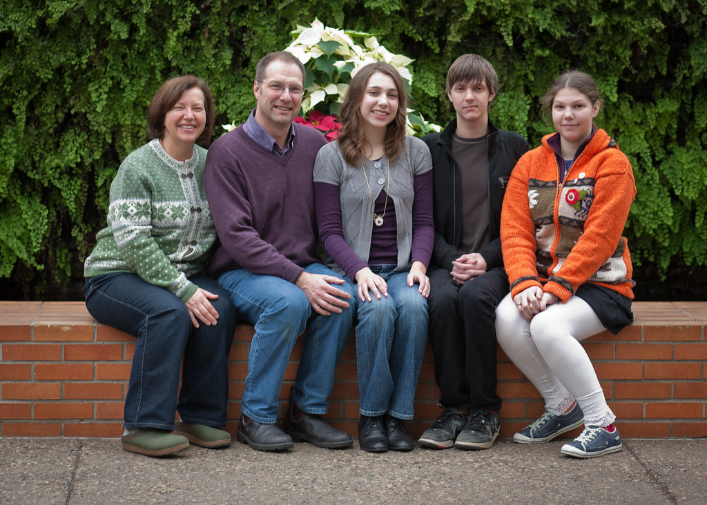 Family with five members sitting on a brick wall