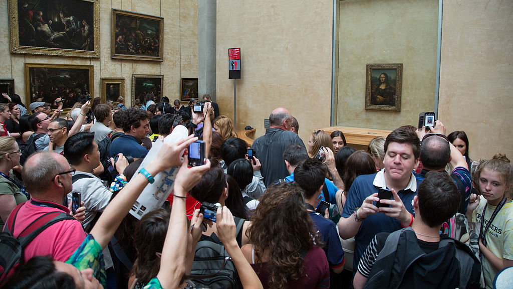 Group of people in a museum with arms raised and camera phones in their hands.