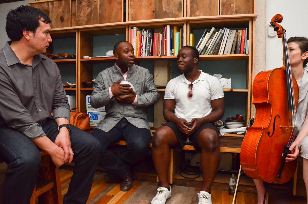 Four people sitting in a room lined with vinyl in the Dorchester Project, one of them is Theaster Gates.