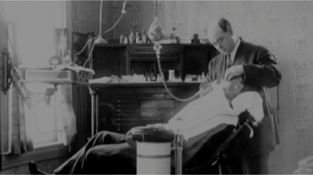 Film still of a man having his teeth pulled by a dentist