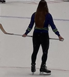 back of a woman with hockey stick and skates