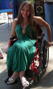 smiling young woman in wheelchair wearing green dress