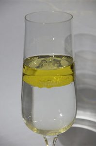 Glass containing two unmixed layers of liquid. Yellow liquid lies on top of a lower layer of clear liquid.