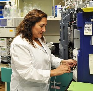 A woman in a lab coat adjusts a piece of equipment in a laboratory