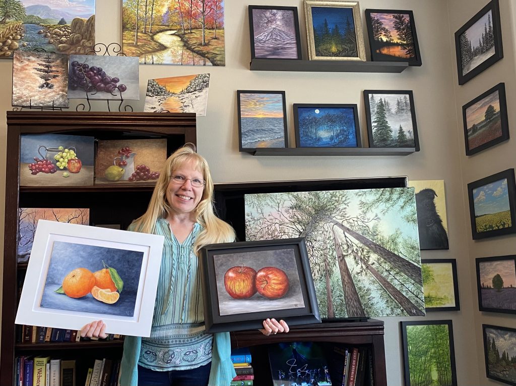 woman poses with paintings