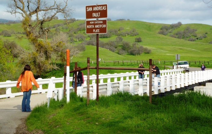 The San Andreas Fault at Parkfield in central California. The person on the far left is standing on the Pacific Plate and the person at the far side of the bridge is on the North American Plate. The bridge is designed to slide on its foundation.