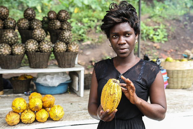 An image of a woman in Ghana holding a cacao bean
