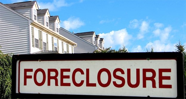 A photo of a foreclosure sign in front of a house