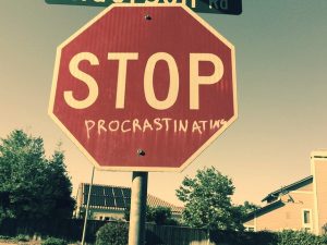 a stop sign with the word &quot;procrastination&quot; painted beneath the word &quot;stop&quot;