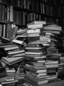 several large messy stacks of books on a table in a library