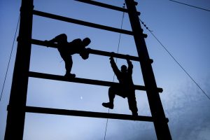 two soldiers in twilight scaling a giant ladder on an obstacle course