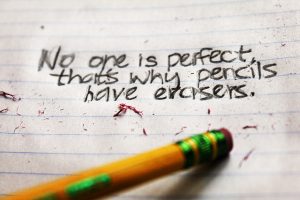 photo of a pencil eraser attempting to erase the words "no one is perfect, that's why we have erasers" written in ink