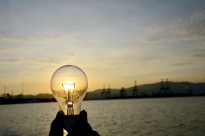 photo of someone holding a clear light bulb in front of a sunrise or sunset