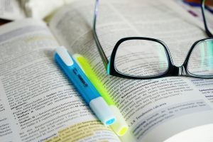 glasses and highlighter pens sitting on an open textbook