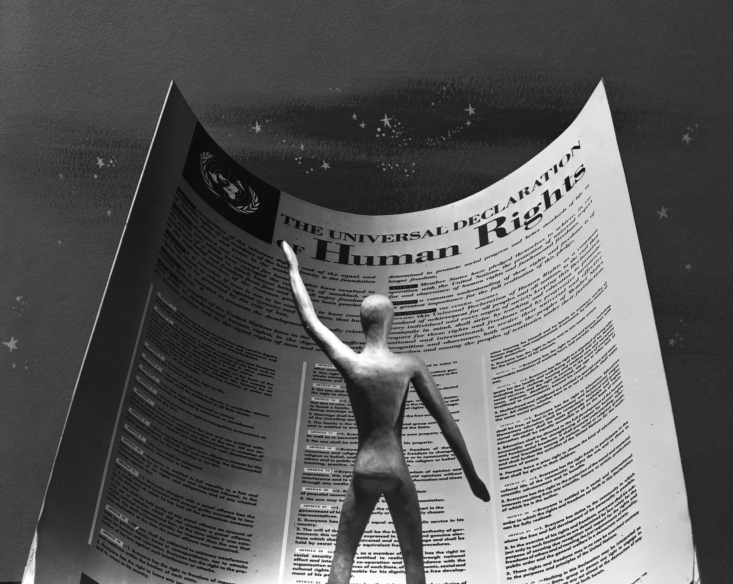 Photo illustration of a figure standing in front of a paper by the universal declaration of human rights bill