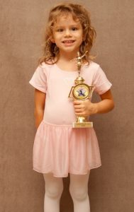 Young girl smiling, holing a participation award.