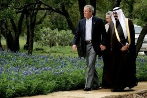 President George W. Bush holding hands with Crown Prince Abdullah of Saudi Arabia as they walk together.