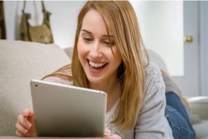 Woman smiling while looking at a tablet.