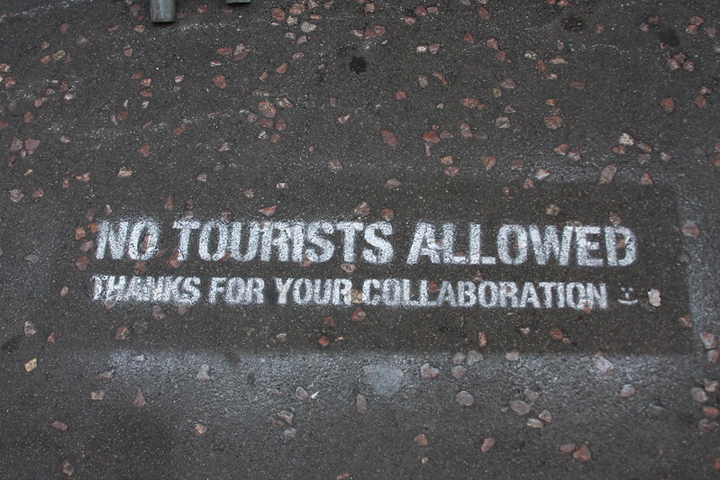 Painted text on a street saying "No tourists allowed. Thanks for your collaboration."
