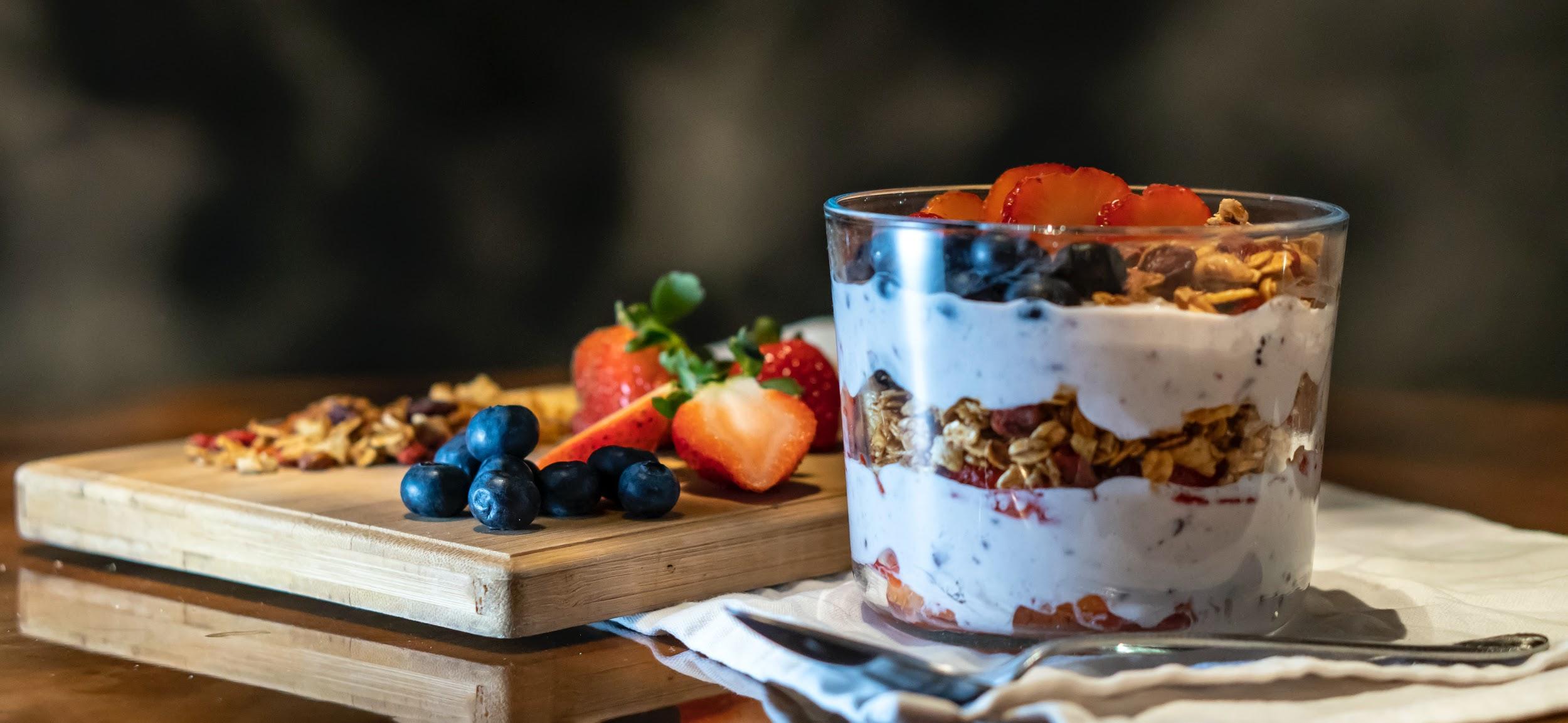 A cup of yogurt with granola and berries