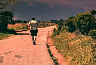 A larger man jogging on a path out in nature.
