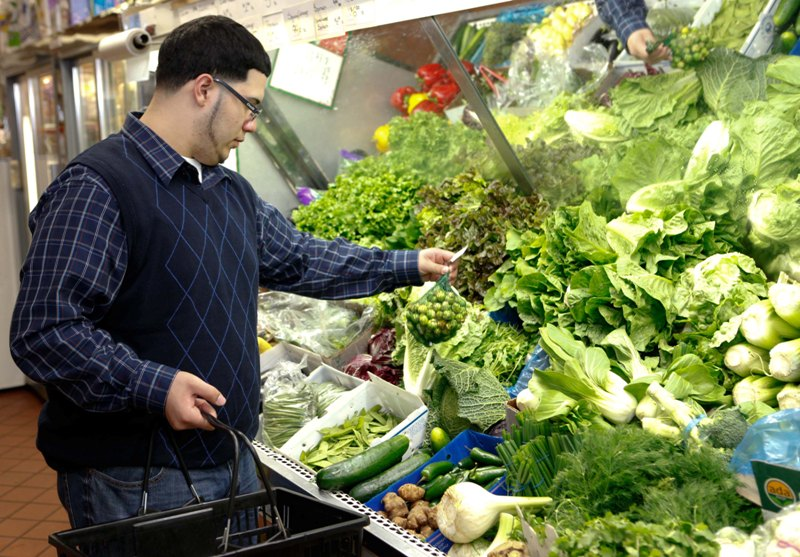 A well-dressed man shops for fresh produce at a grocery store.