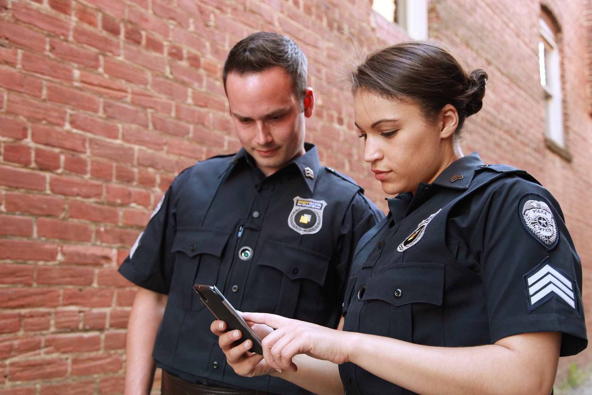 Two police officers looking at an electronic device