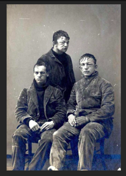 Three college-aged White men have bruised faces and disheveled clothing.