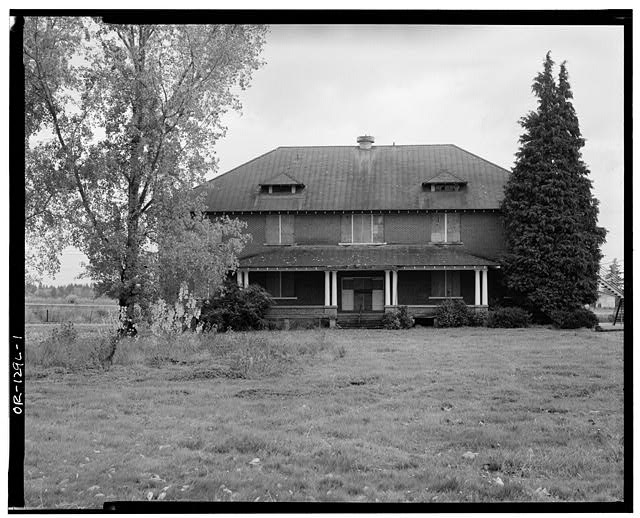 Black and white photograph of the Chemawa Indian School. The yard is overgrown and the windows are boarded up.