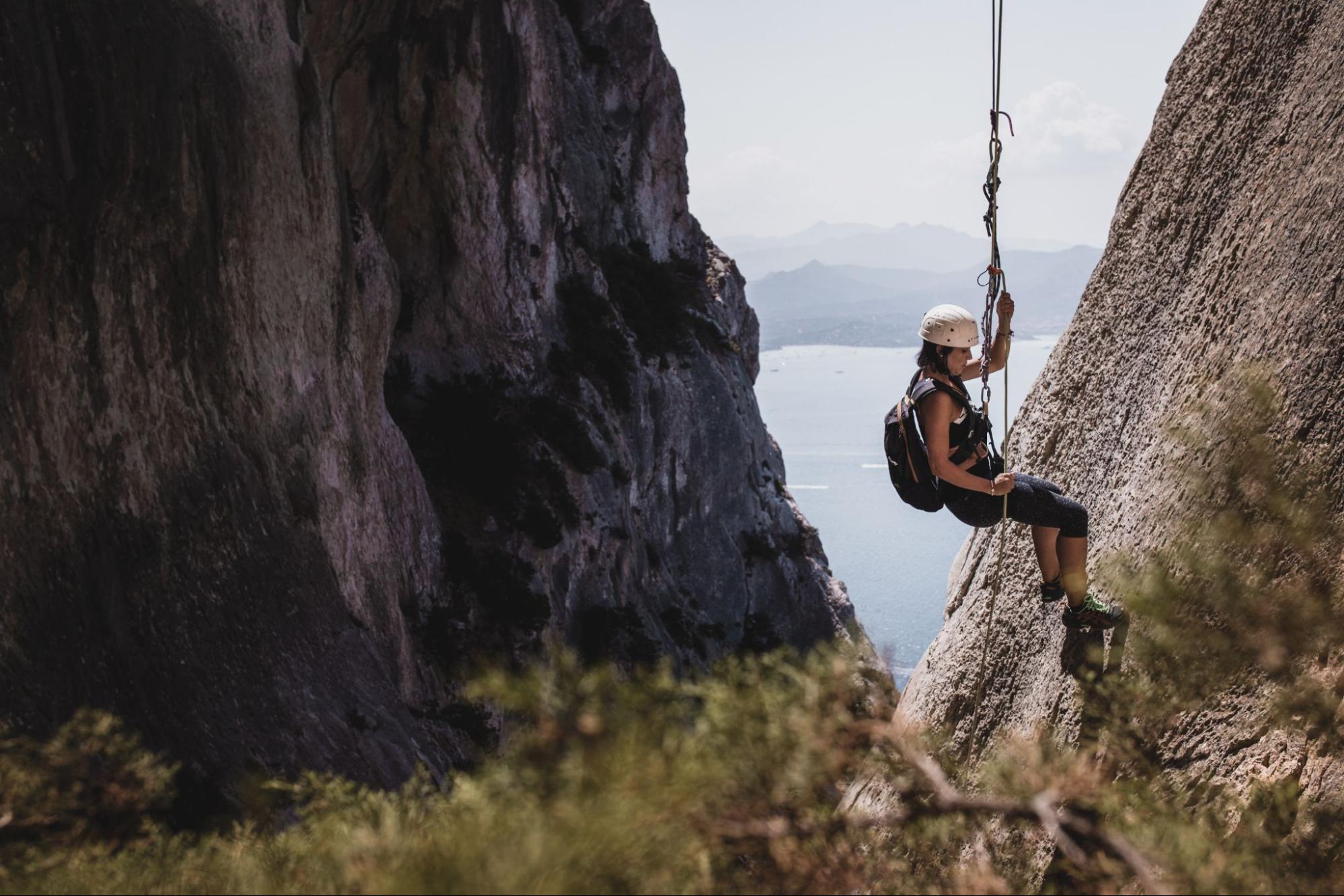 A woman is rappelling down a cliff