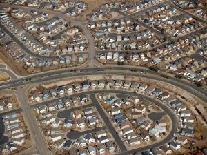 Aerial view of a subdivision with several cul de sacs with large houses that have similar shapes. Very little trees or green.