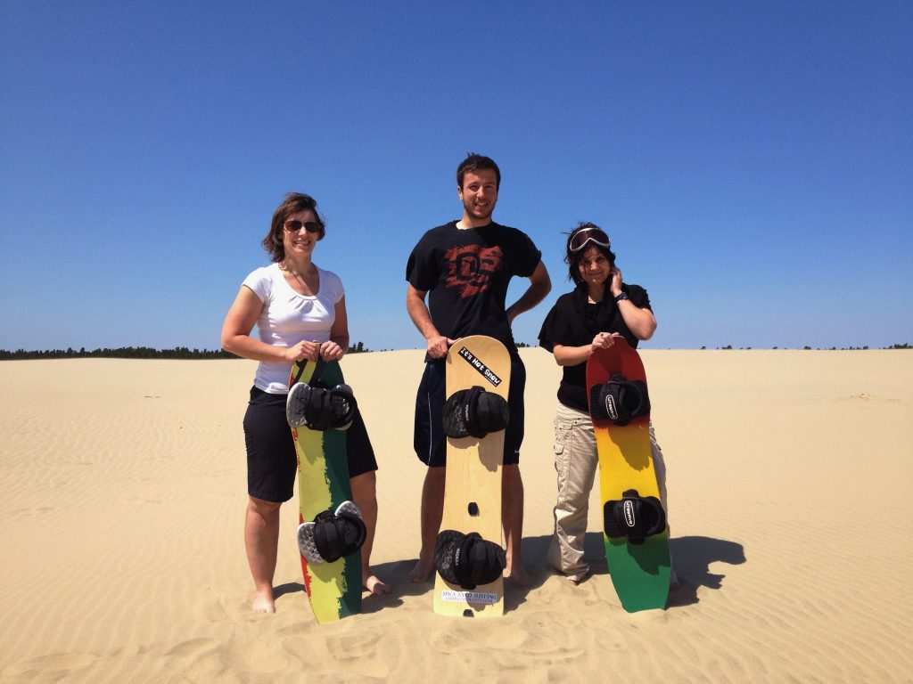 three people on sand dune holding sh