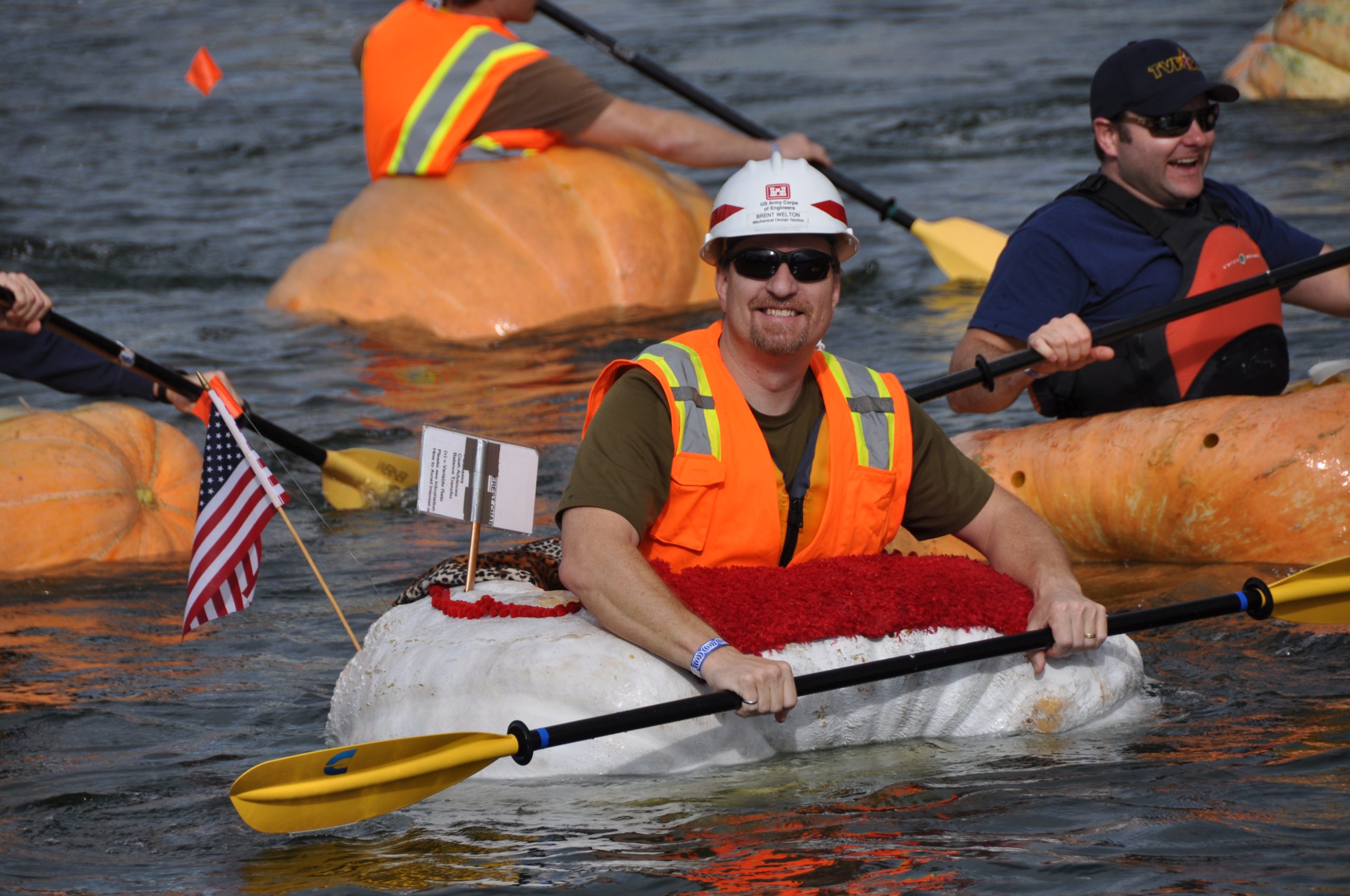 men in giant pumpkins on the river