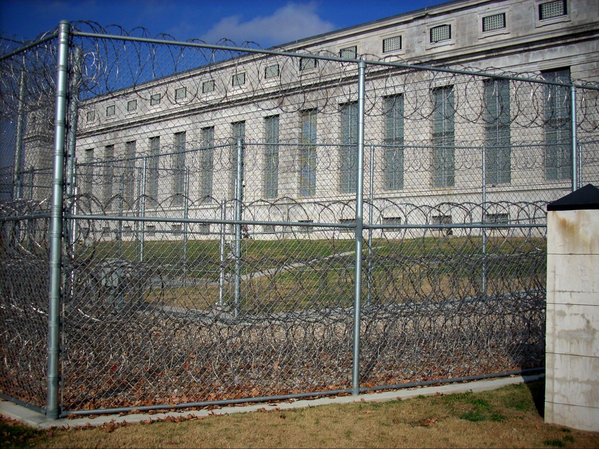 Two rows of chain length fence with razor wire enclosing the prison.