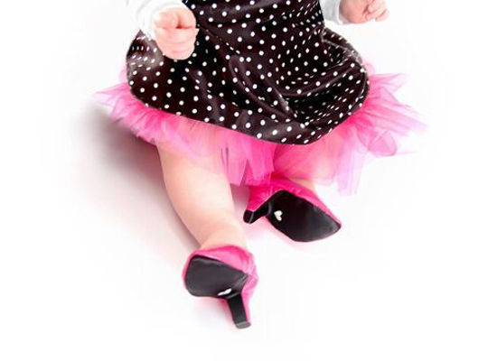 Baby from waist down with frilly dress and pink high heels.