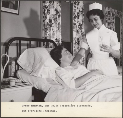 An indigenous woman in a nurses uniform stands next to a patient in a hospital bed.