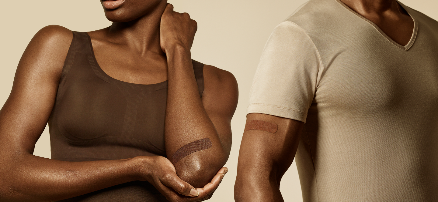 Two dark-skinned people wear bandages on their arms that match their skin tone.