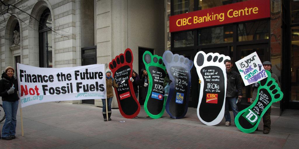 People holding large signs about fossil fuels on a city street