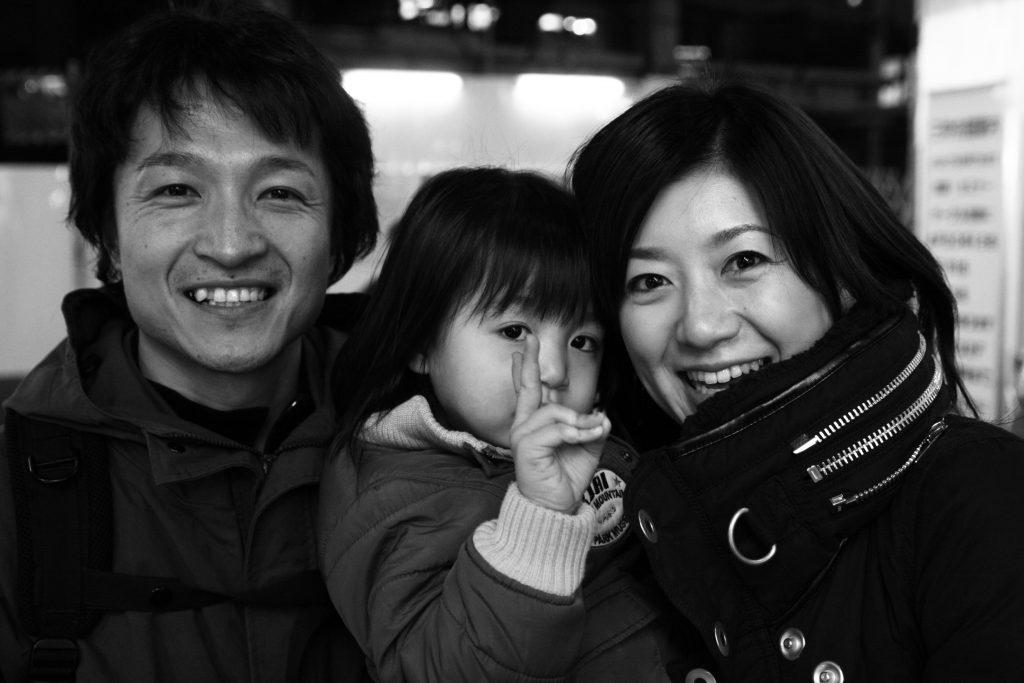 Dark haired man, child and woman holding each other close and smiling