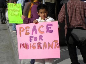 A young boy in Minneapolis holds a a poster that reads &quot;Peace for Immigrants&quot;
