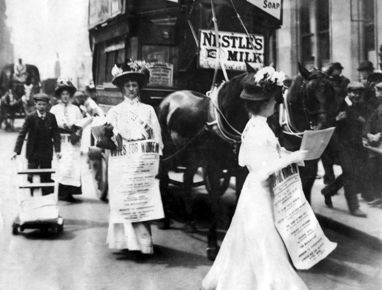 Photograph of women in 1908 in London England carrying signs and marching for women&#039;s right to vote.