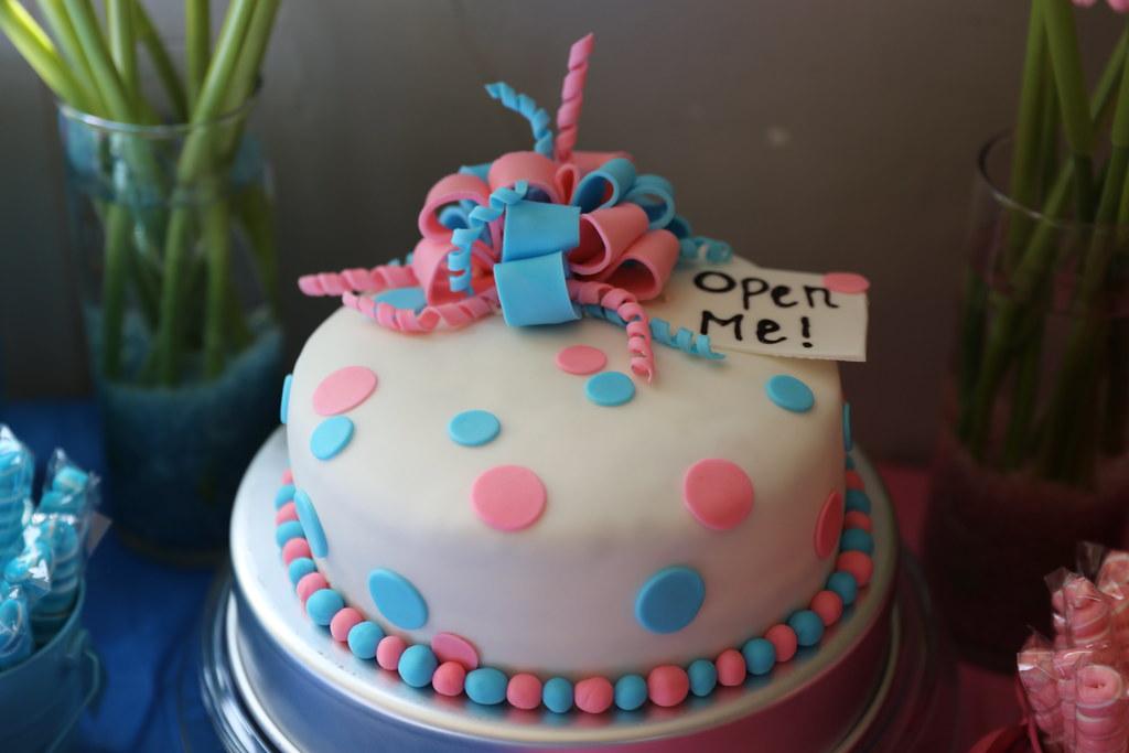 White layer cake with pink and blue trim labeled "open me"