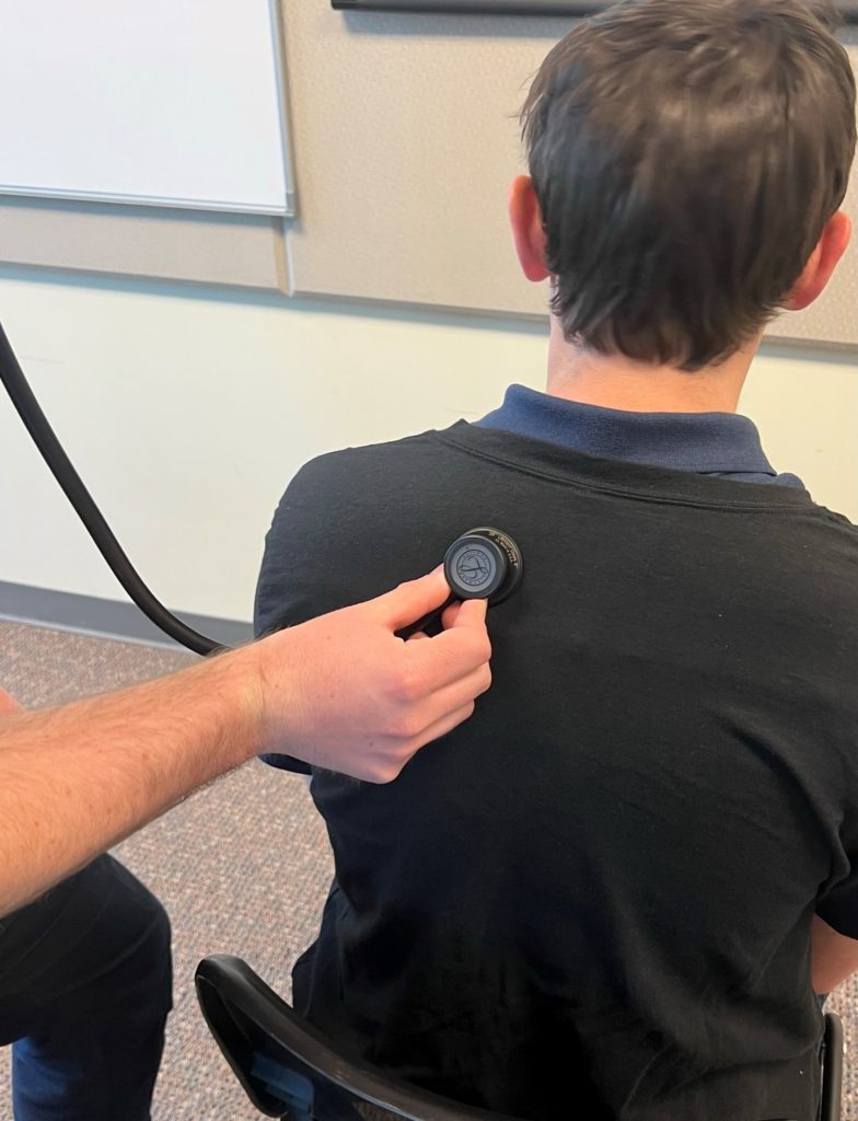 A person using a stethoscope to listen to a patient's left posterior upper lobe.