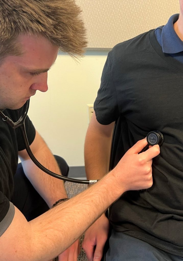 A person using a stethoscope to listen to a patient's anterior left lower chest wall, left lower lobe.